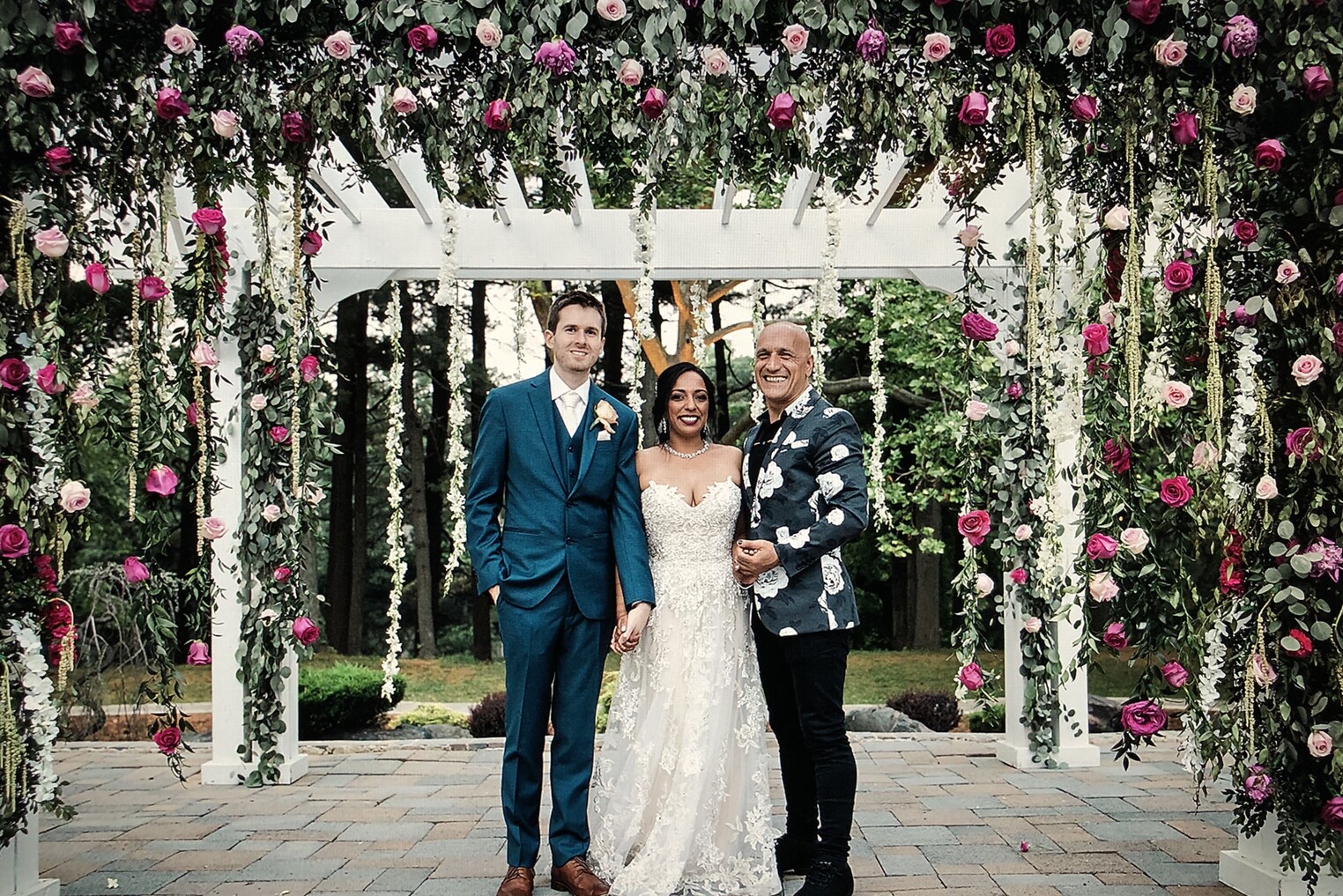 Sandro with a couple beneath a floral arch